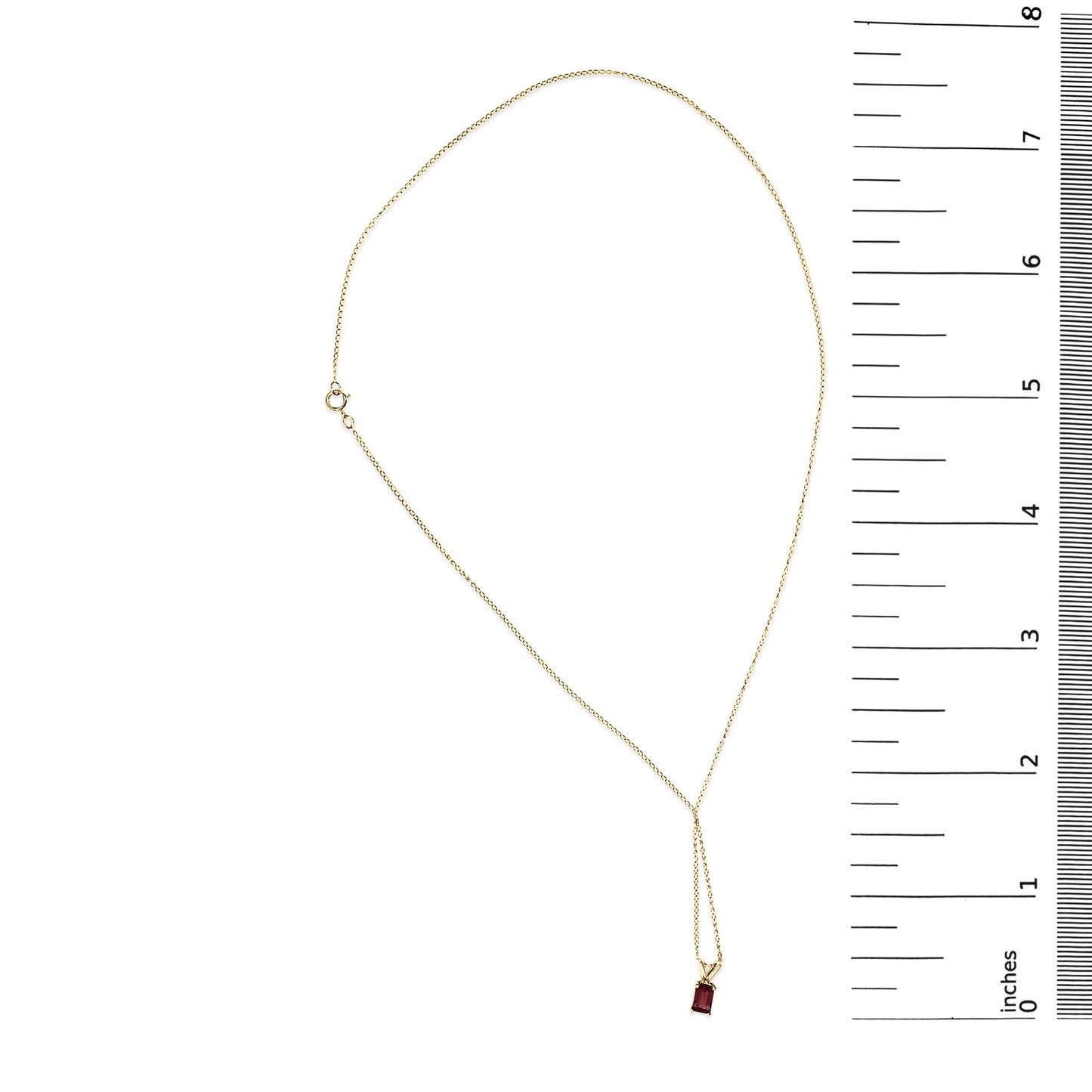 Yellow metal necklace with a red emerald-shaped gemstone pendant in a 4-prong setting, shown flat on a scale, top-down angle.
