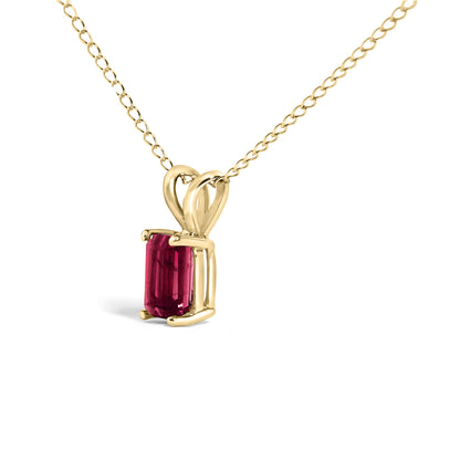 Close-up front angle of a yellow metal necklace featuring a rectangular red gemstone in a four-prong setting.