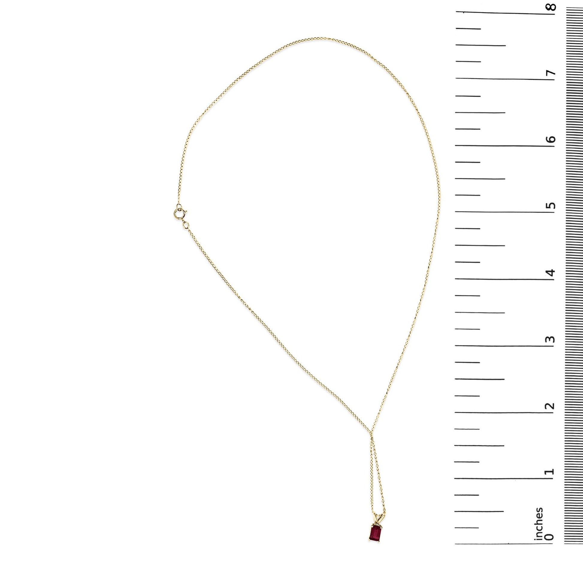 Yellow necklace with a small red rectangular gemstone pendant in a 4-prong setting, shown flat on a white surface next to a ruler for scale, top-down view.