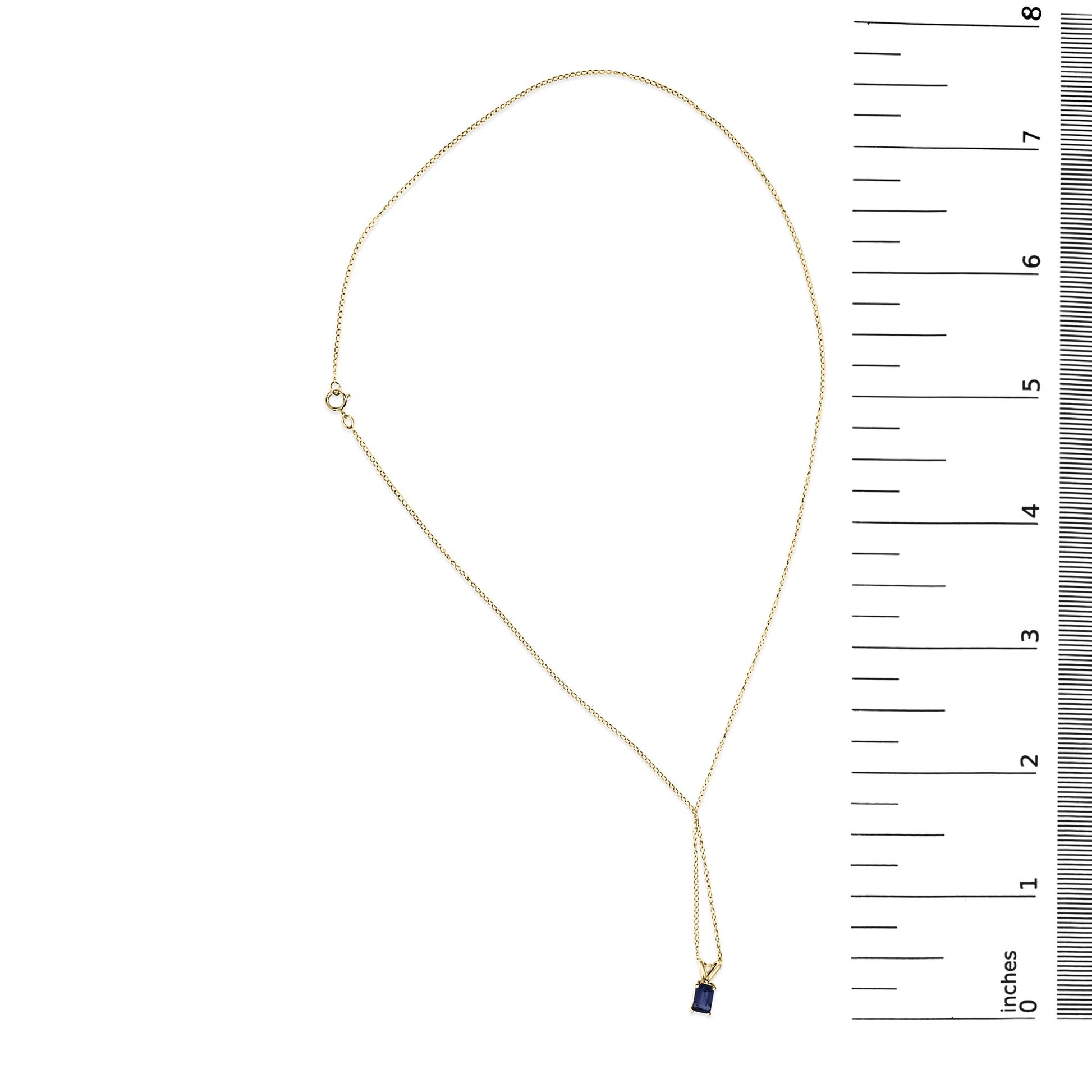 Yellow necklace with a blue rectangular gemstone pendant in a four-prong setting, shown flat on a white background with ruler for scale, top-down view.