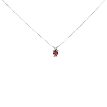 Close-up front view of a white metal necklace with a heart-shaped red gemstone pendant in a three-prong setting.
