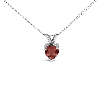 Front angle close-up of a white metal necklace with a heart-shaped red gemstone pendant in a three-prong setting.