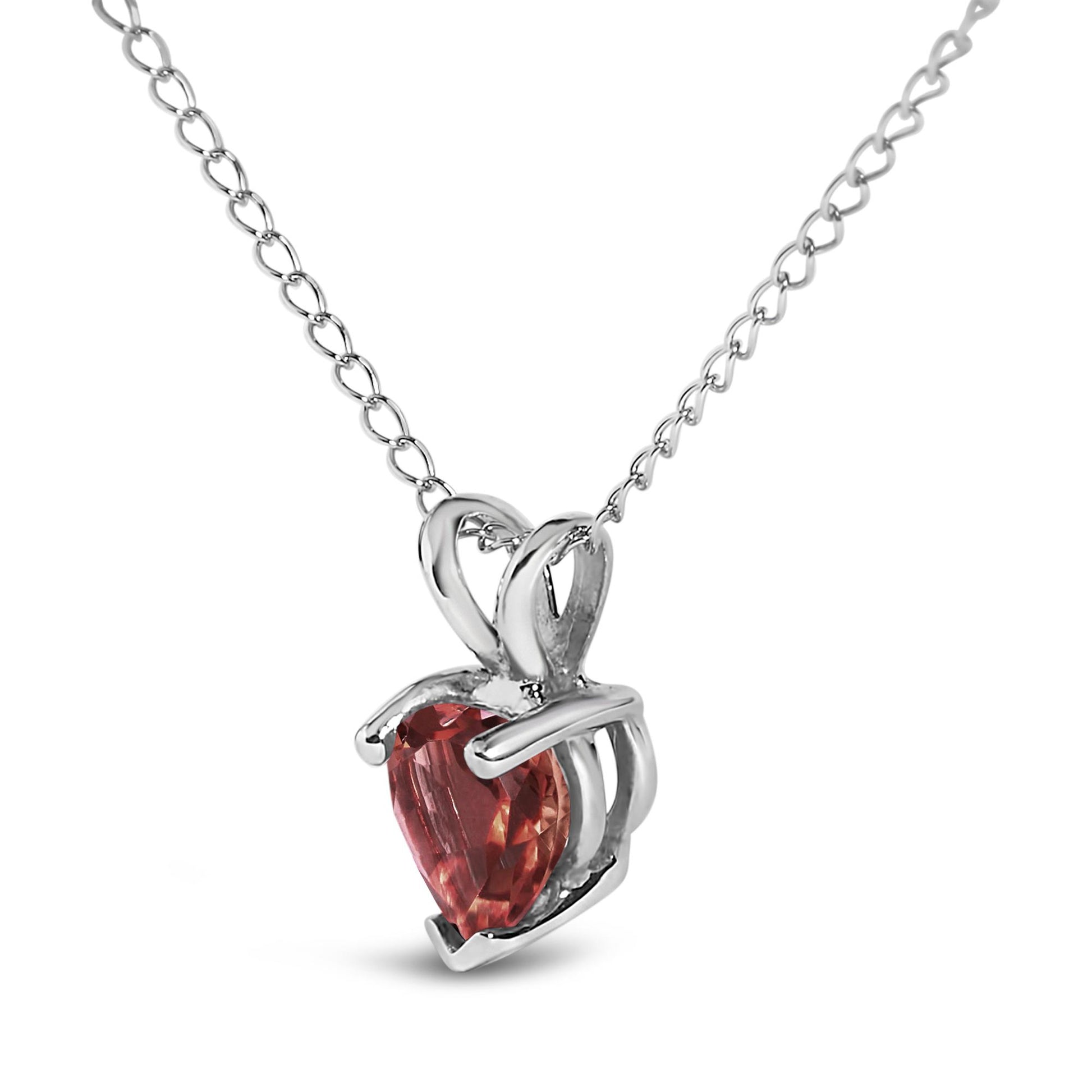White metal necklace with a heart-shaped red gemstone pendant in a three-prong setting, shown in a front angle close-up.