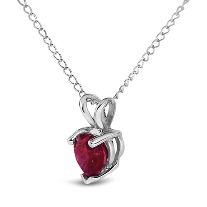 Close-up front view of a white metal necklace featuring a heart-shaped red gemstone pendant with a three-prong setting.