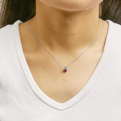 Close-up front view of a model wearing a white necklace with a heart-shaped red gemstone pendant in a 3-prong setting.