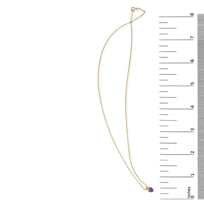 Yellow metal necklace with a heart-shaped purple gemstone pendant in a 3-prong setting, shown flat on a white background next to a ruler for scale.