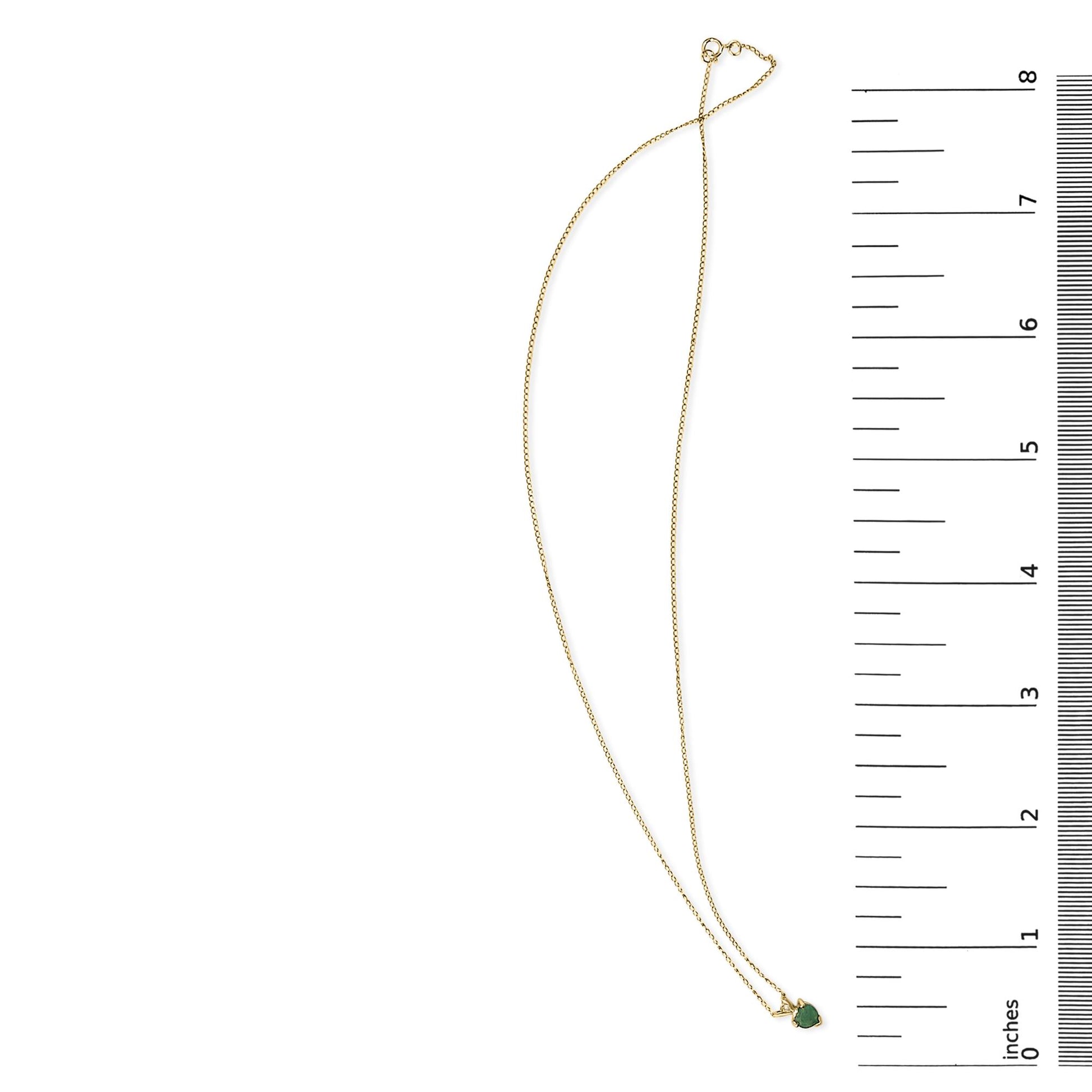 Yellow necklace with a small heart-shaped green gemstone pendant, shown on a scale from above.