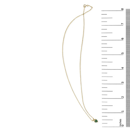 Yellow necklace with a small heart-shaped green gemstone pendant, shown on a scale from above.