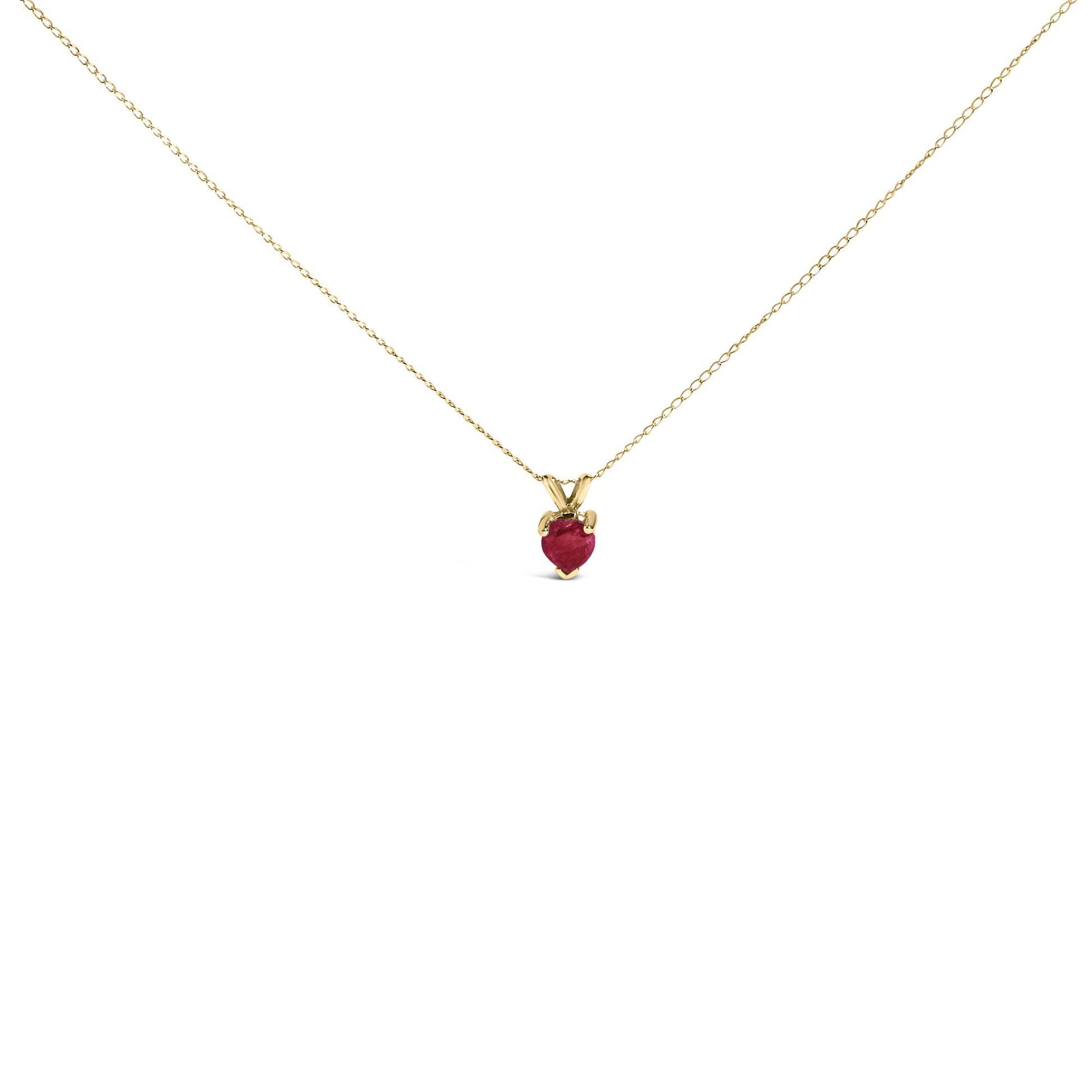 Close-up front view of a yellow metal necklace with a heart-shaped red gemstone pendant in a three-prong setting.