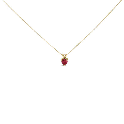 Close-up front view of a yellow metal necklace with a heart-shaped red gemstone pendant in a three-prong setting.