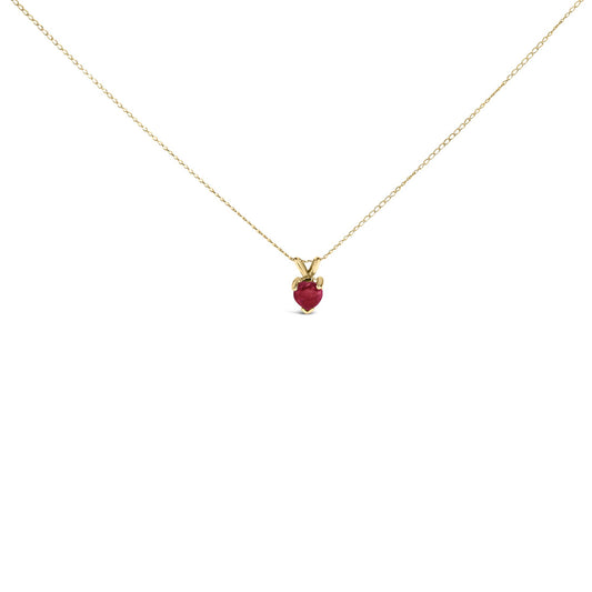 Close-up front view of a yellow metal necklace with a heart-shaped red gemstone pendant in a three-prong setting.