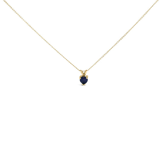 Close-up front view of a yellow metal necklace with a heart-shaped blue gemstone pendant in a three-prong setting shown on a white background.