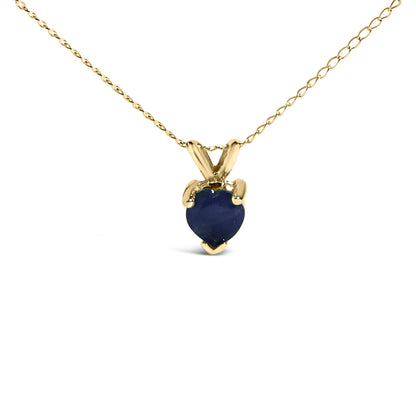 Close-up front view of a yellow metal necklace with a heart-shaped blue gemstone pendant in a three-prong setting.