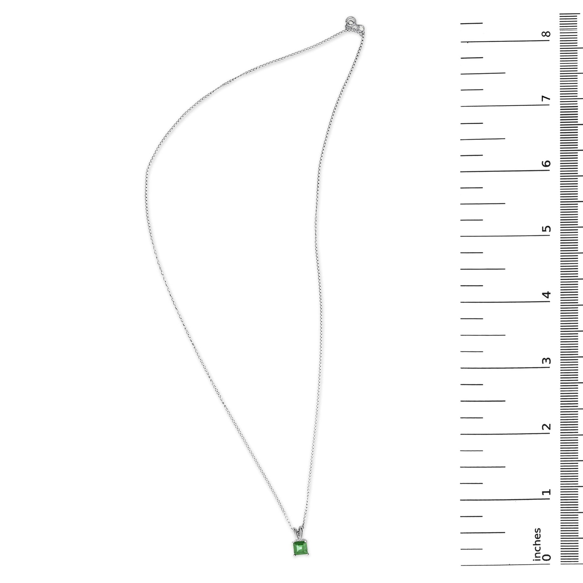 White necklace with a princess-shaped green gemstone pendant in a 4-prong setting, shown flat beside a measuring scale, top-down angle.