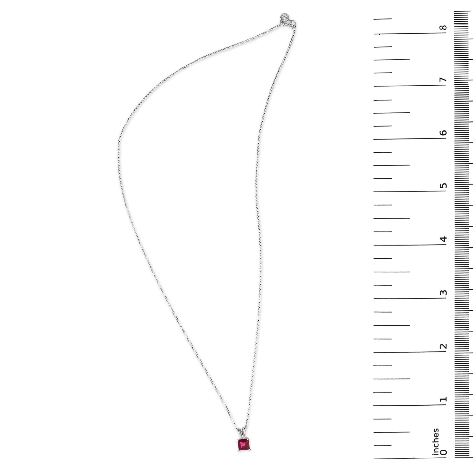 White metal necklace with a princess-cut red gemstone pendant in a 4-prong setting shown flat on a white background with a ruler scale on the right side.