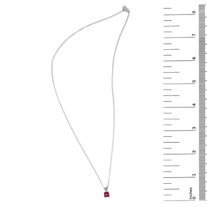 White metal necklace with a princess-cut red gemstone pendant in a 4-prong setting shown flat on a white background with a ruler scale on the right side.