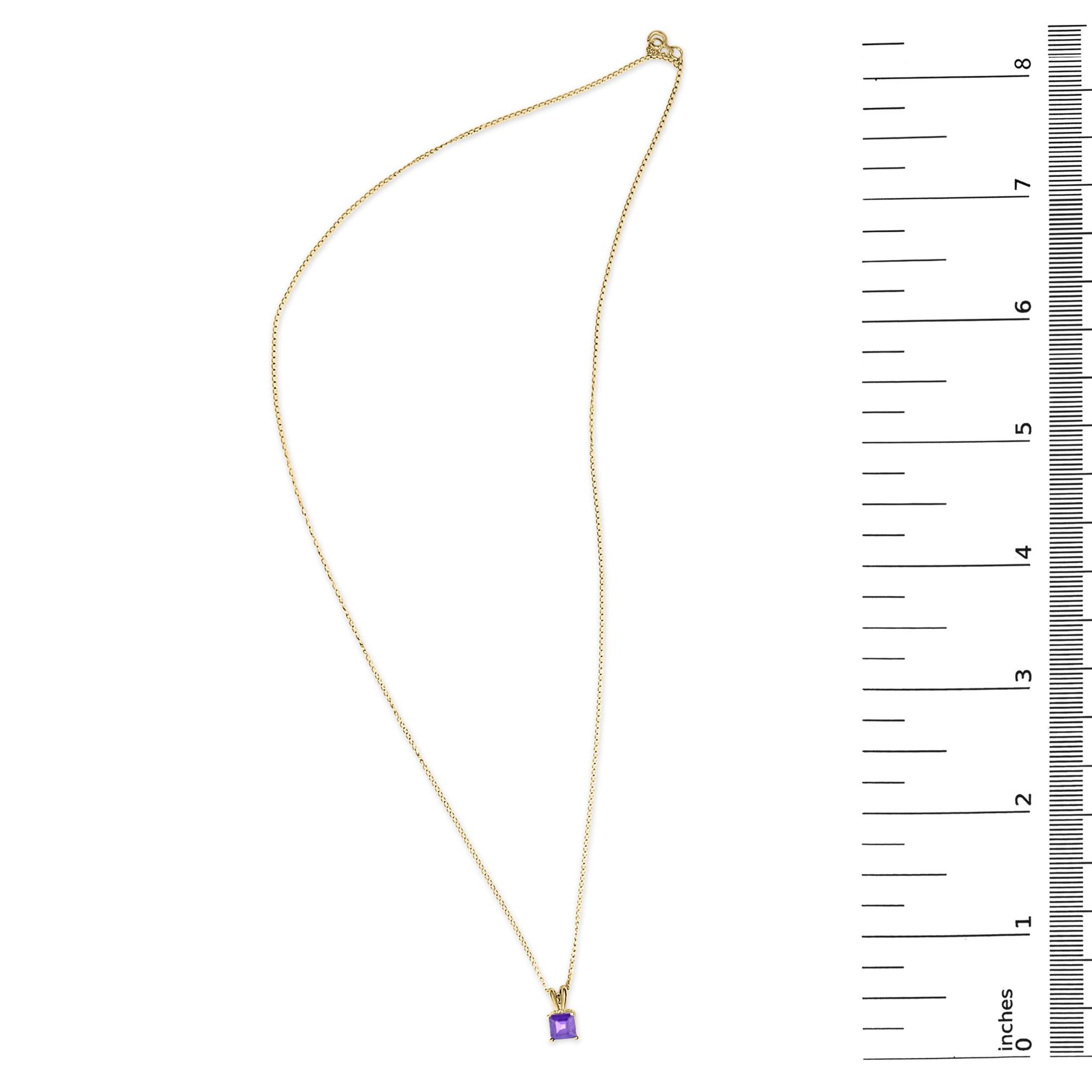 Yellow metal necklace with a square purple gemstone pendant in a four-prong setting, shown on a flat surface with a measuring scale on the right, shot from above.
