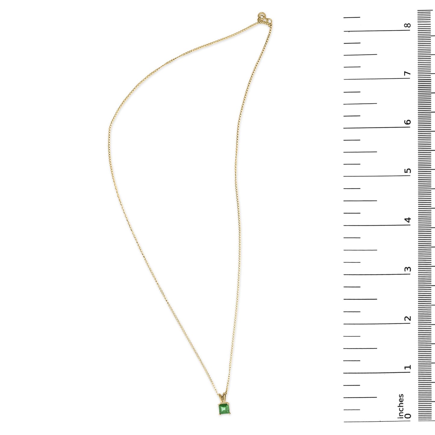 Yellow metal necklace with a green princess-shaped gemstone in a four-prong setting, shown from above on a scale.