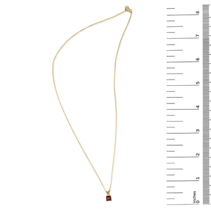 Yellow necklace with a square red gemstone pendant shown flat next to a ruler for scale, top-down angle.