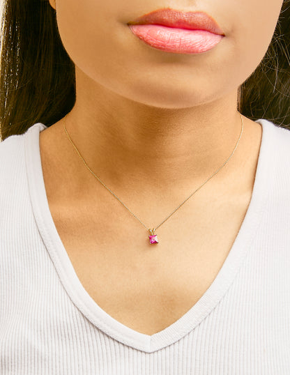 Necklace with a square red gemstone pendant in a four-prong setting on a fine yellow chain, shown worn on a model from the front.