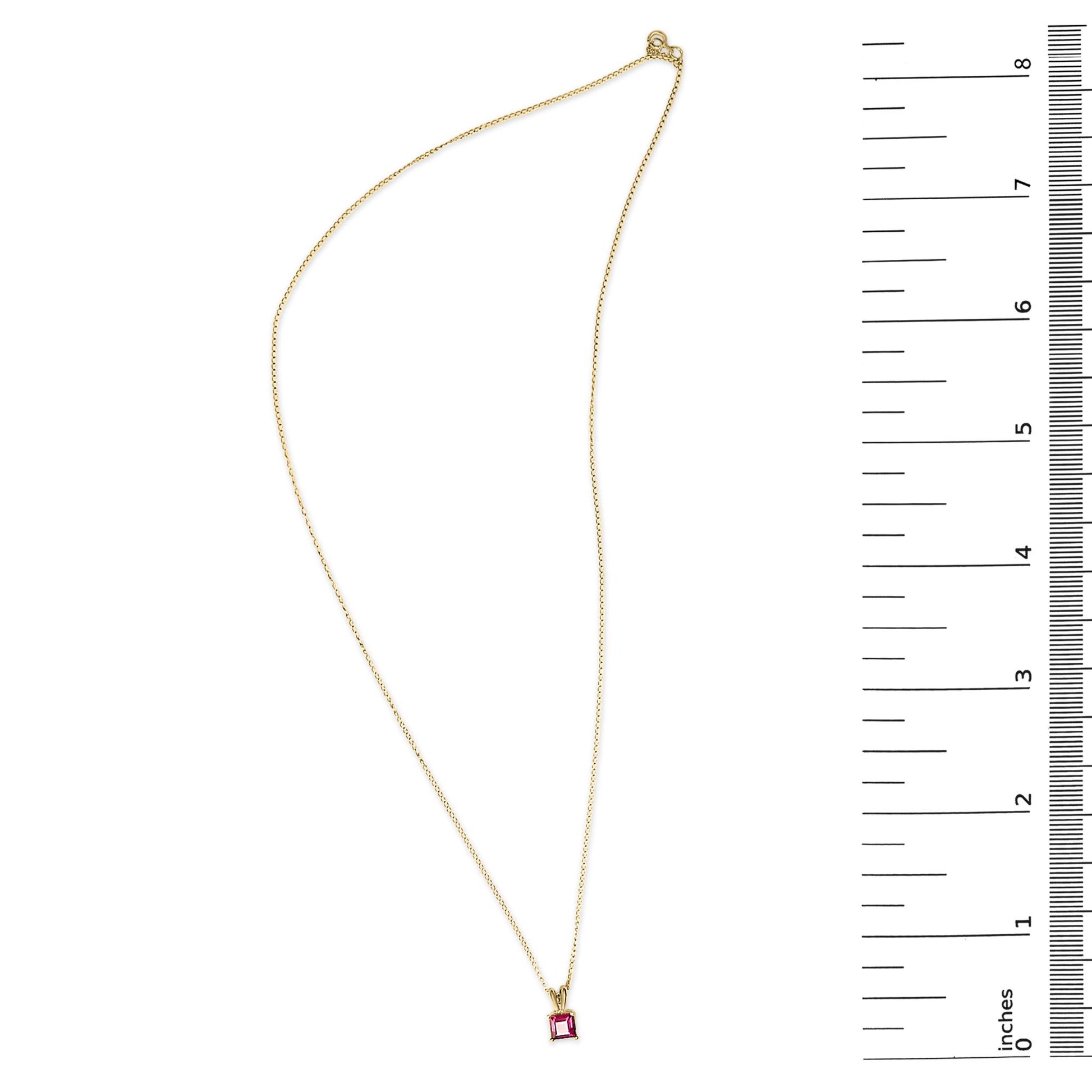 Yellow necklace with a princess-shaped red gemstone pendant in a 4-prong setting, shown on a scale from a top-down angle.