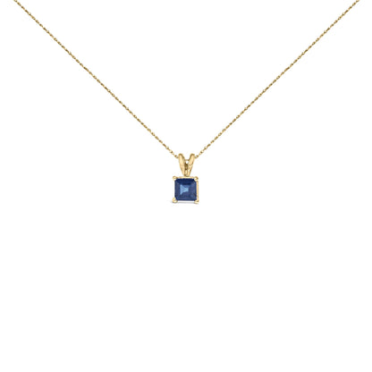 Front view of yellow metal necklace with a single blue princess-shaped gemstone pendant in a four-prong setting.
