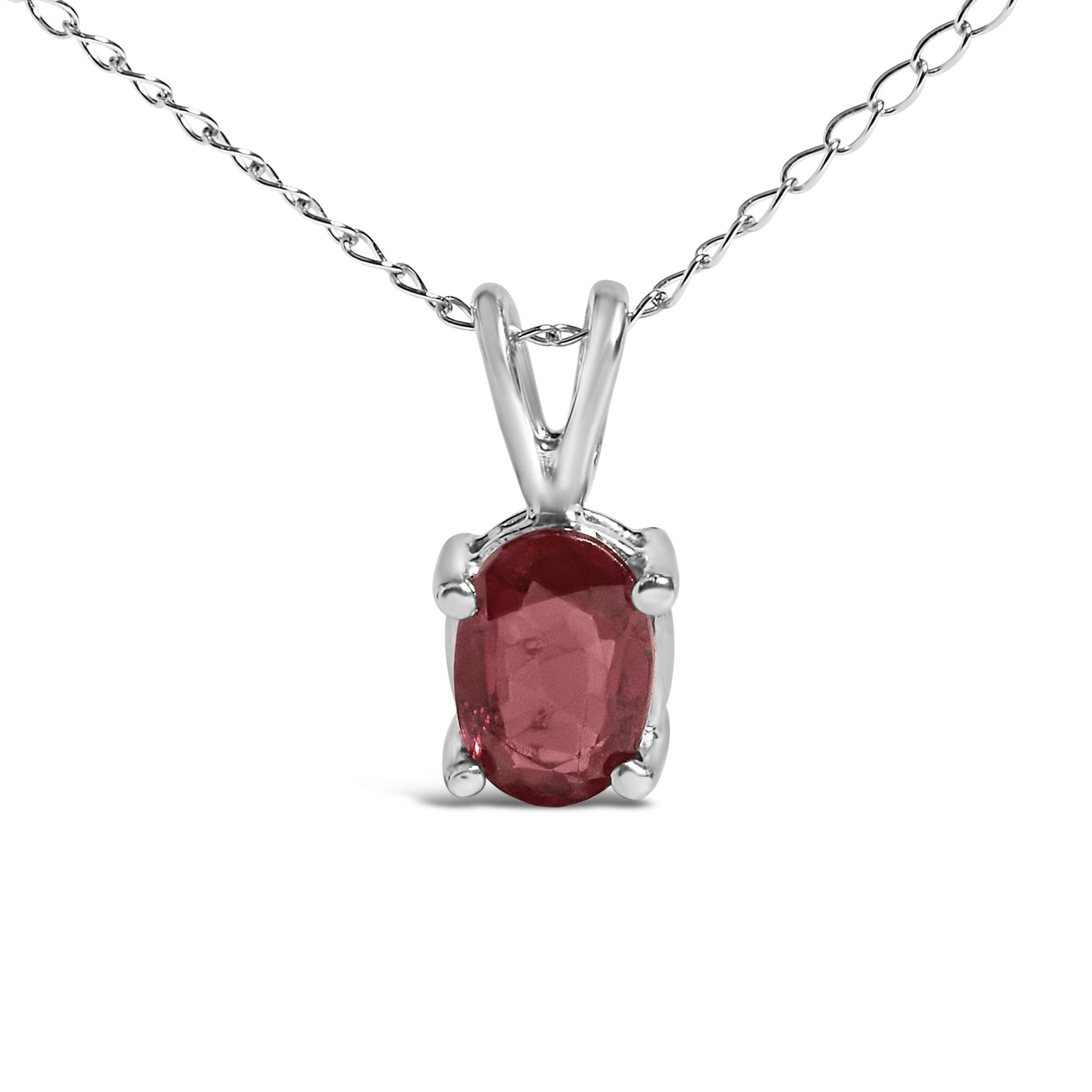Close-up front view of a white metal necklace with an oval-shaped red gemstone pendant held by four prongs on a chain.