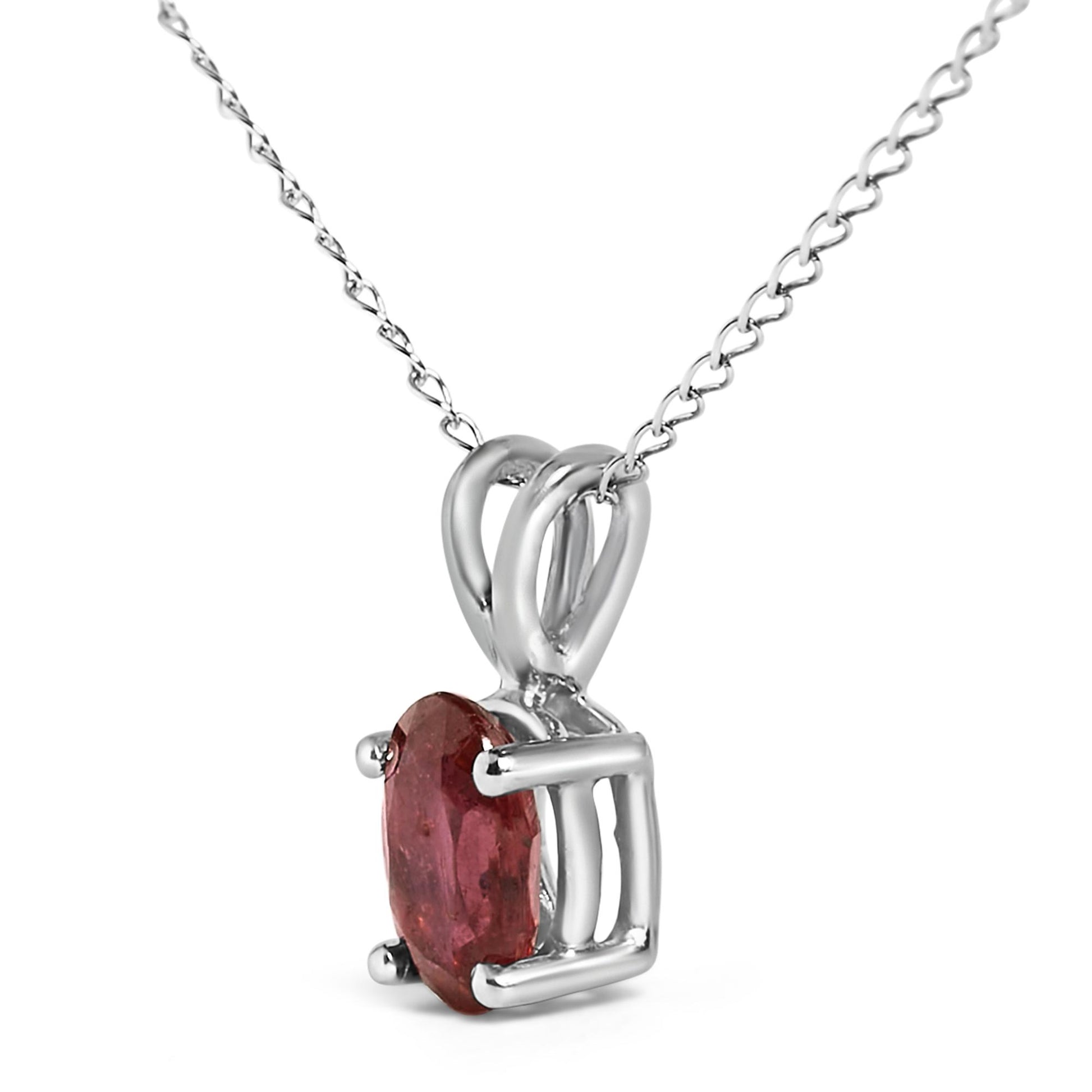 Close-up angled view of a white metal necklace featuring an oval red gemstone held by a four-prong setting.