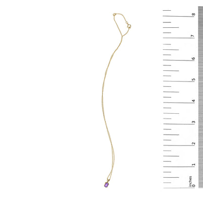 Yellow necklace with a small oval purple gemstone pendant in a four-prong setting, shown flat next to a ruler for scale, top-down view.