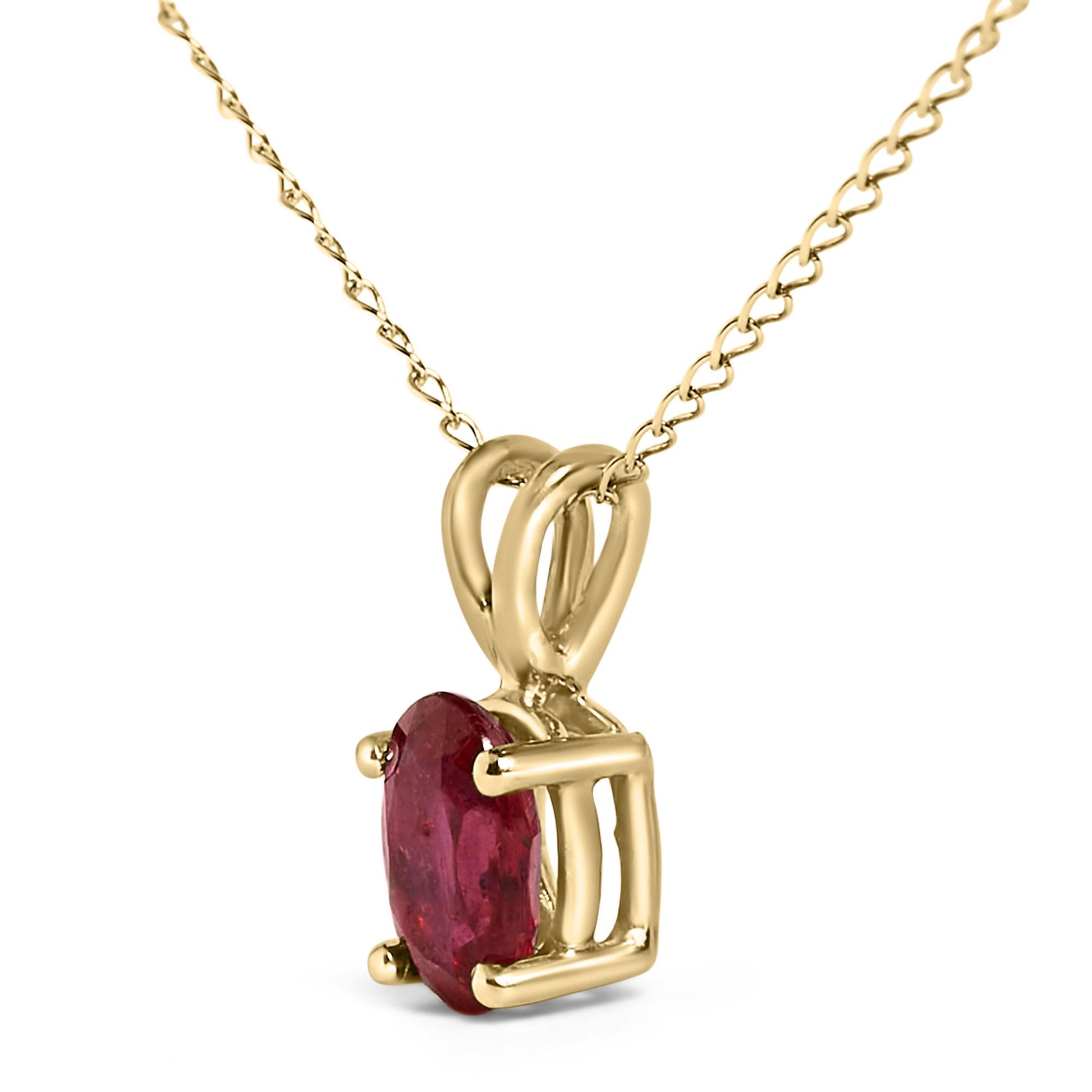 Close-up front angle of a yellow metal necklace with an oval-shaped red gemstone held by a four-prong setting.