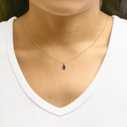 Yellow necklace with an oval blue gemstone in a 4-prong setting, shown worn on a model in a front-facing close-up shot.