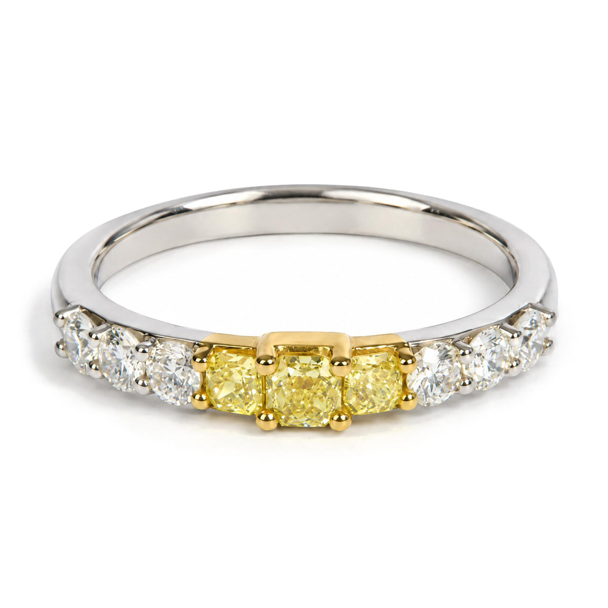 Close-up angled view of a ring featuring three yellow radiant-shape gemstones in prong settings centered on a yellow metal section, flanked by white round gemstones in prong settings on a white metal band.