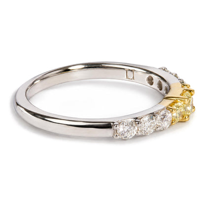 Close-up front angled view of a ring featuring a white metal band with prong-set round white gemstones and a yellow metal section with prong-set radiant yellow gemstones.