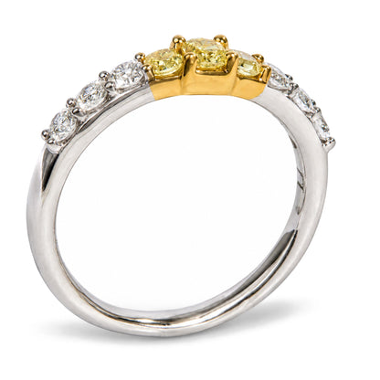 Close-up front angle of a ring featuring a band with mixed yellow and white metal colors, set with three yellow radiant-shaped gemstones in prong settings at the center, flanked on each side by multiple white round-shaped gemstones in prong settings.