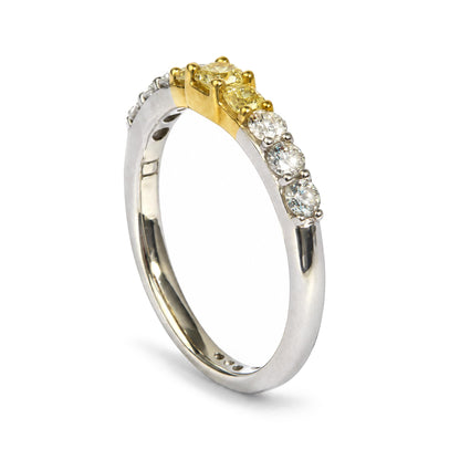 Close-up angled side view of a two-toned ring featuring white and yellow metal. The ring is set with three yellow radiant-shaped gemstones in the center and a row of round white gemstones flanking each side in prong settings.