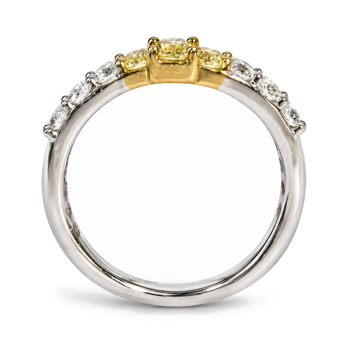 Close-up side angle of a ring with a yellow and white metal band, featuring three yellow radiant-shaped gemstones in prong settings at the center, flanked by multiple white round-shaped gemstones in prong settings along the band.