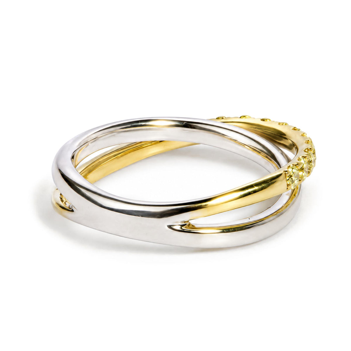 Close-up front view of intertwined rings, one in yellow metal with round yellow gemstones in prong settings, and another in white metal.
