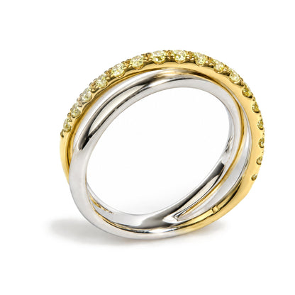 Close-up angle of two intertwined rings, one with a smooth white metal band and the other yellow metal band set with round prong-set yellow gemstones.