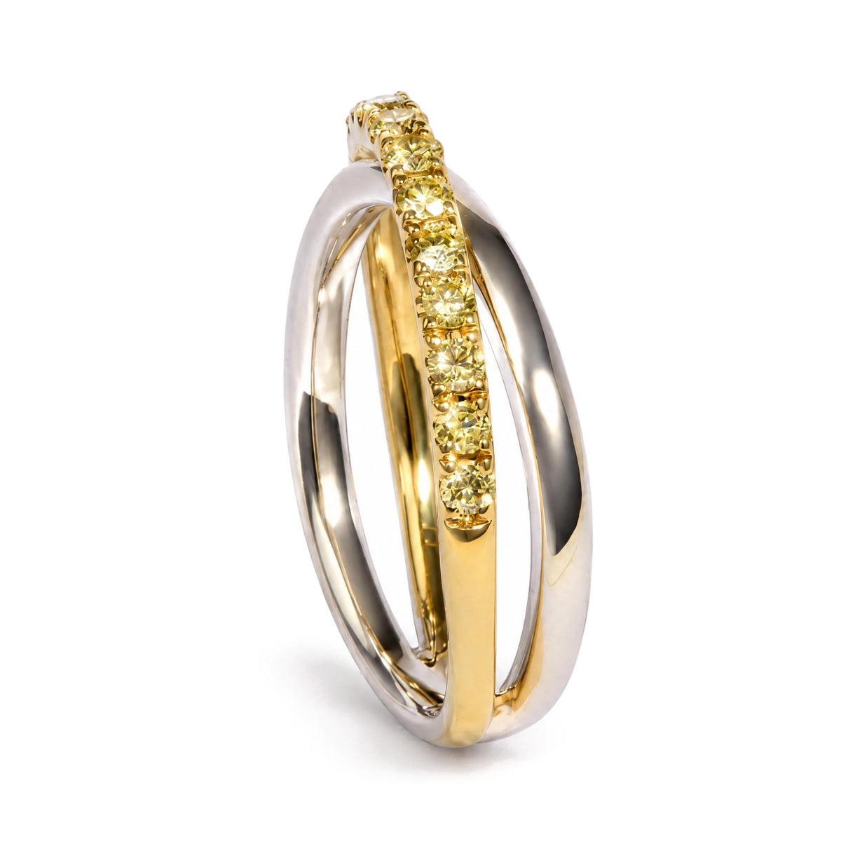 Close-up angled shot of intertwined rings, one in yellow metal set with round yellow gemstones in prong settings, and two in white metal.