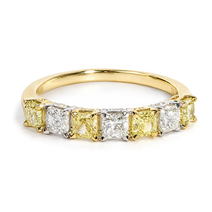 Close-up front angle of a ring with alternating cushion-shaped yellow and white gemstones in prong settings on yellow and white metal bands.