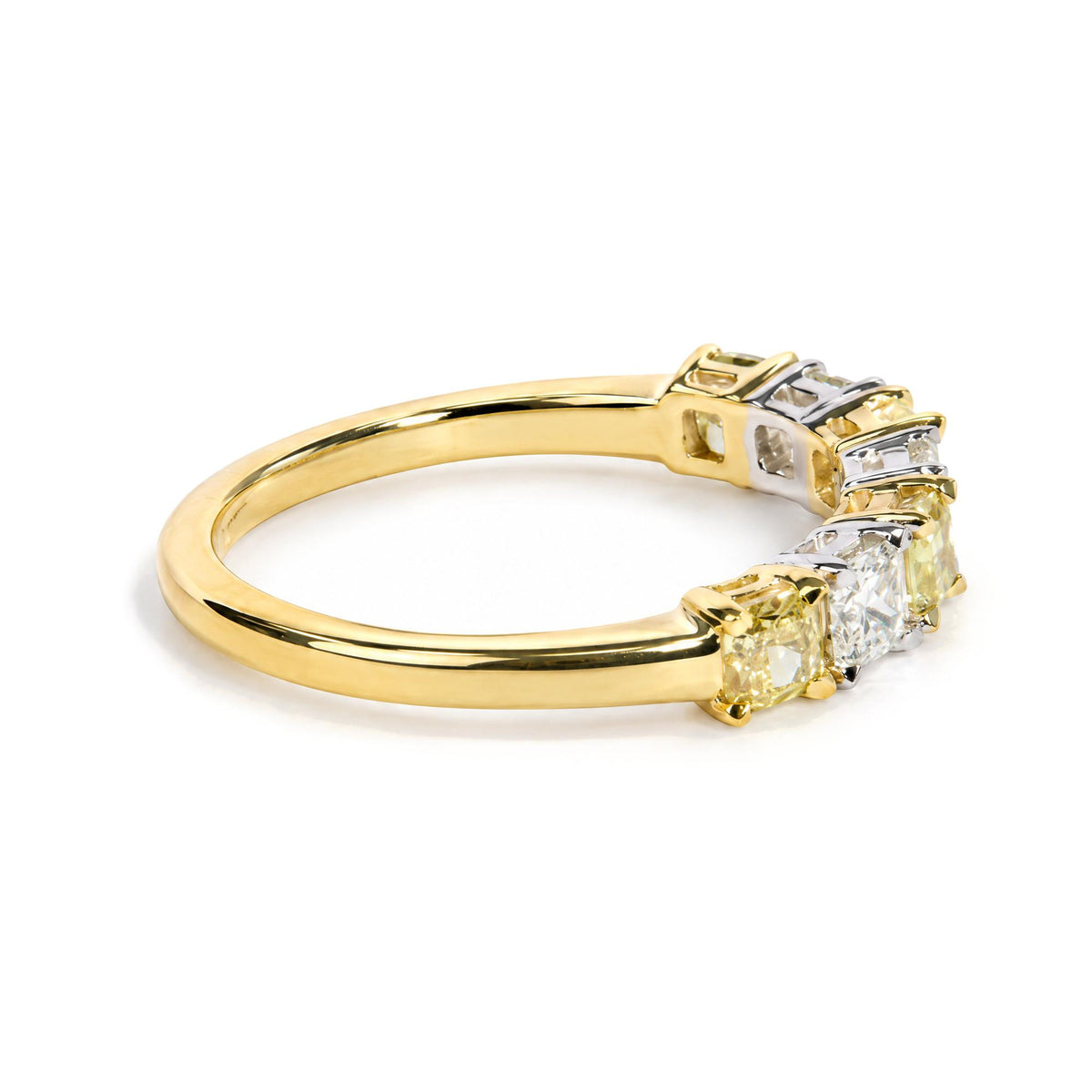 Close-up of a yellow and white metal ring shown on a white background from a side angle, featuring cushion-shaped yellow and white gemstones in prong settings along the top.