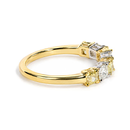 Close-up of a yellow and white metal ring shown on a white background from a side angle, featuring cushion-shaped yellow and white gemstones in prong settings along the top.