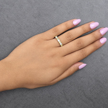 Ring with alternating yellow and white cushion-shaped gemstones in prong settings on a yellow and white band, shown worn on a model's hand, angled top-down view.