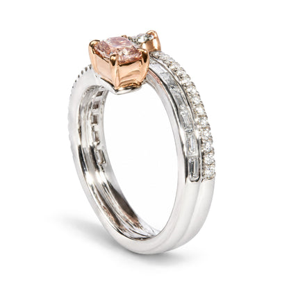 Close-up angled view of a white and rose metal ring with a cushion-shaped pink gemstone in prong setting, an oval-shaped green gemstone in prong setting, baguette-shaped white gemstones in channel setting, and round-shaped white gemstones in prong setting.