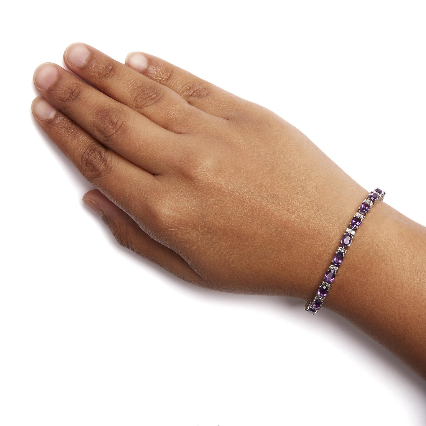White metal bracelet with oval purple gemstones and round white gemstones in shared prong setting, shown on a model's wrist, top angle.