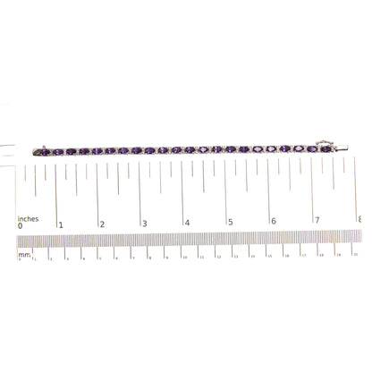 Top-down view of a white metal bracelet with oval-shaped purple gemstones in four-prong settings alternating with round white gemstones in shared prong settings, placed on a ruler for size reference.