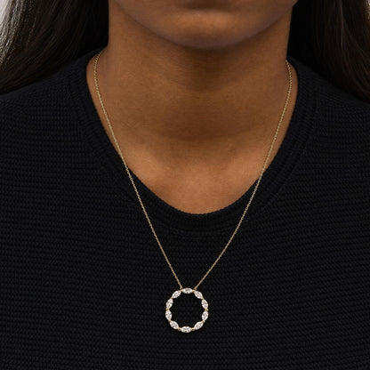 Close-up front view of a model wearing a yellow metal necklace with a circular pendant made of marquise-shaped white gemstones in a shared prong setting.