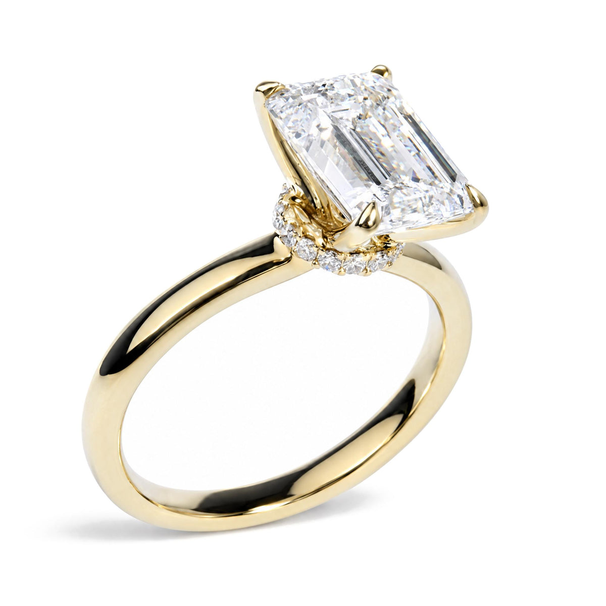Close-up angle of a yellow metal ring with a large emerald-shaped white gemstone in prong setting, surrounded by round white gemstones along the band.