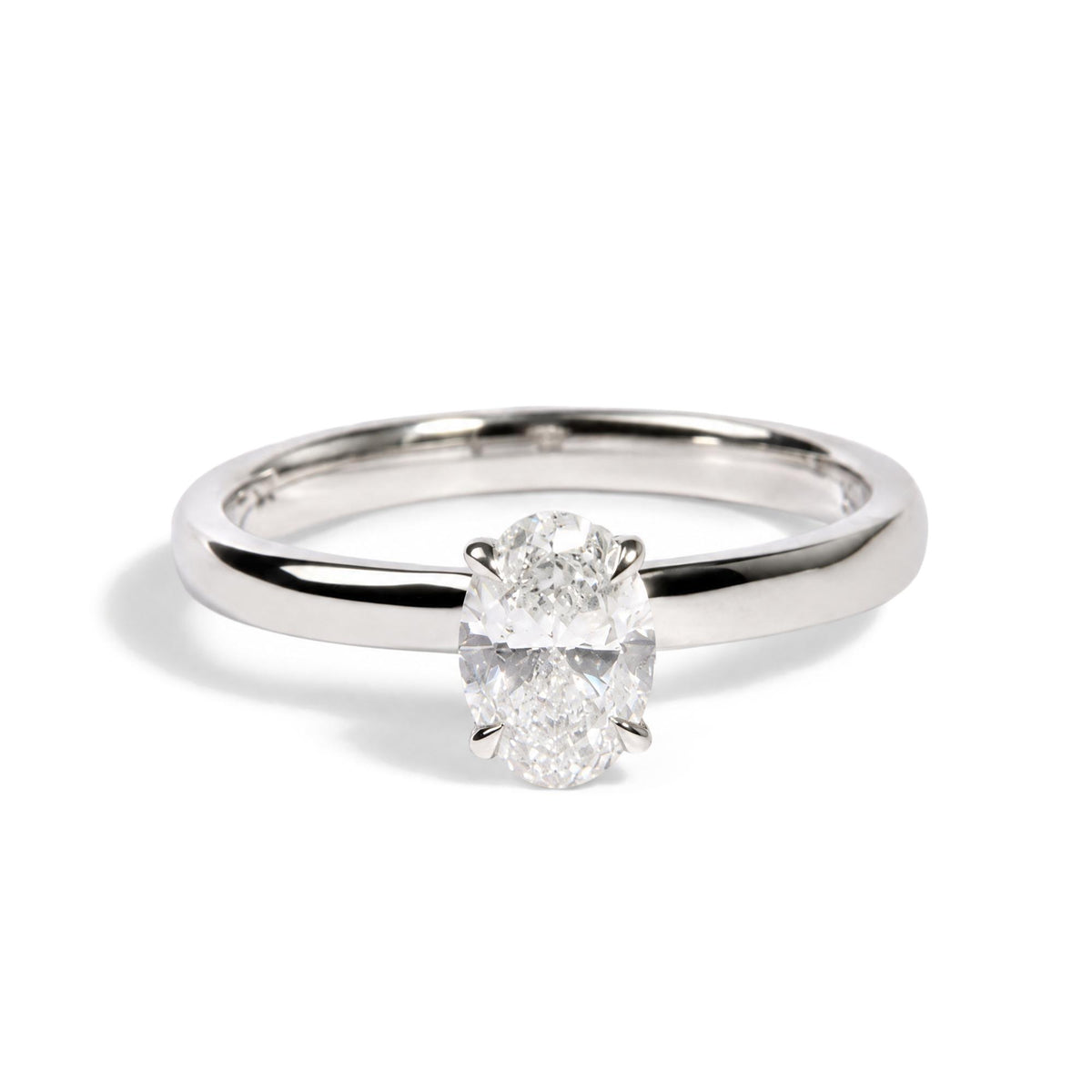 Close-up front angle of a white metal ring featuring a central oval-shaped white gemstone in a 4-prong setting surrounded by smaller round white gemstones in prong settings.