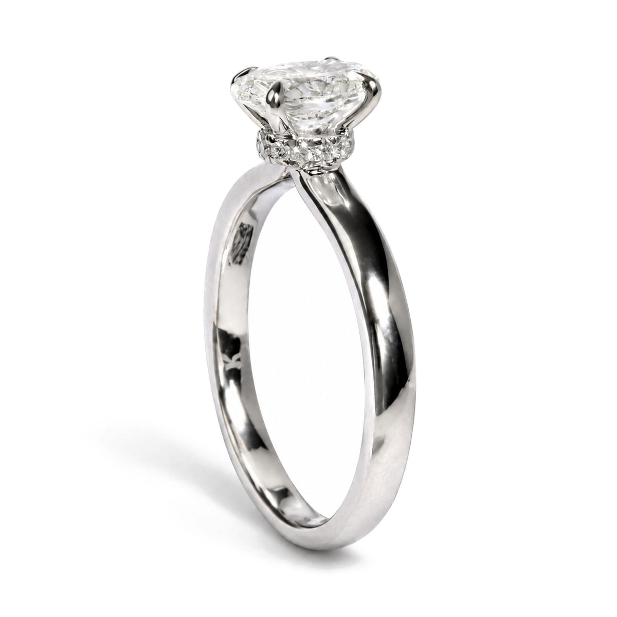 Close-up front angle of a white metal ring featuring one oval-shaped white gemstone held by a four-prong setting, surrounded by multiple round-shaped white gemstones in prong settings along the band.